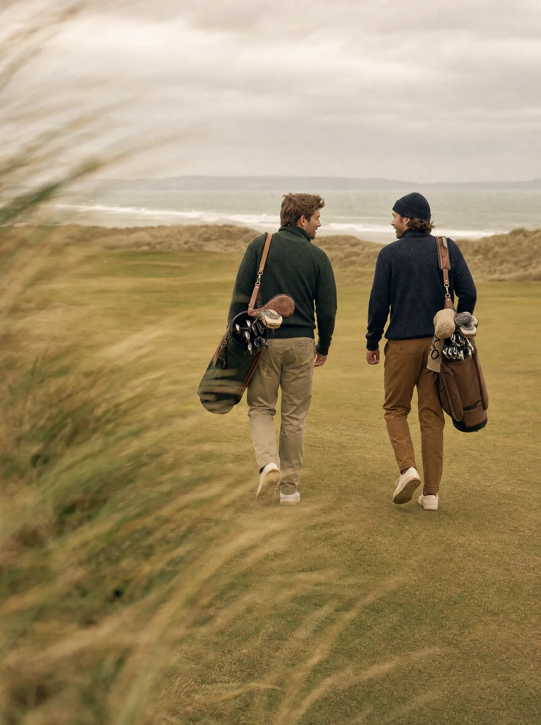 Two golfers walking a coastal links course through the dune grass
